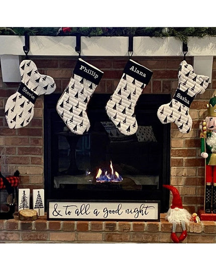 Black metal Annie Stocking Holder from Industrial Farm Co displaying four personalized Christmas stockings with tree patte...