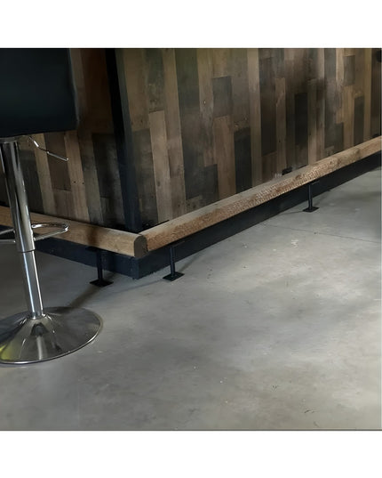Black metal bar foot rail bracket mounted on wooden bar base with rustic wood plank wall background - Industrial Farm Co