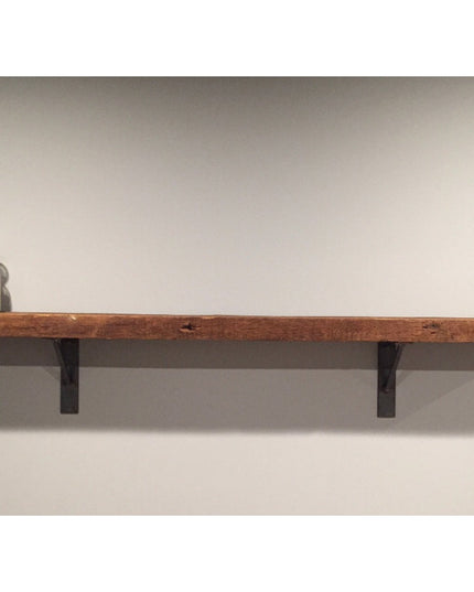 Rustic wooden floating shelf with black metal Oneida brackets mounted on white wall, displaying glass jars with cork stopp...