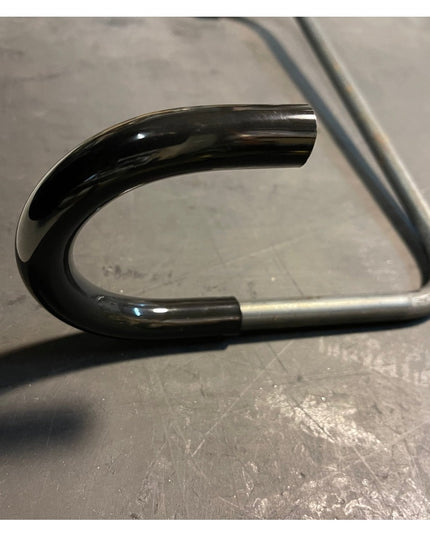 Black powder-coated steel Logan Wall Mounted Bike Rack hook by Industrial Farm Co showing curved design on concrete surface