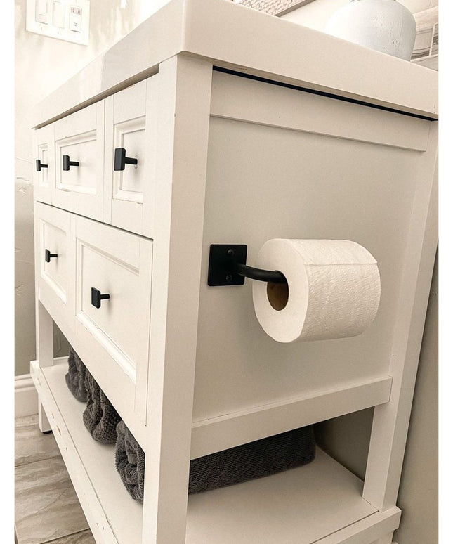The Mitz black metal toilet paper holder by Industrial Farm Co mounted on white farmhouse bathroom vanity with open shelving