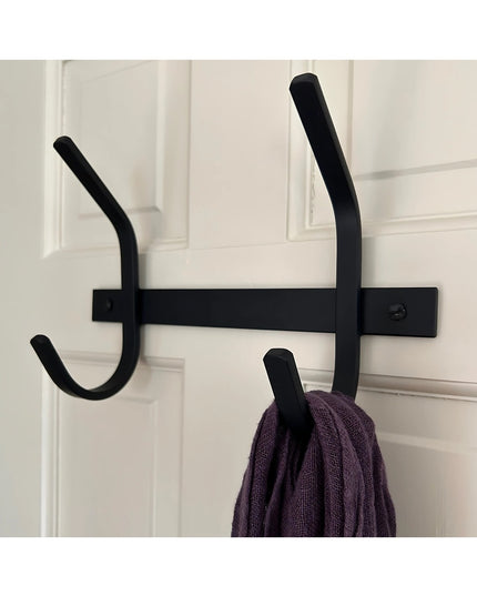 The Meredith Petite Double J black metal coat rack mounted on white door with purple sweater hanging on right hook
