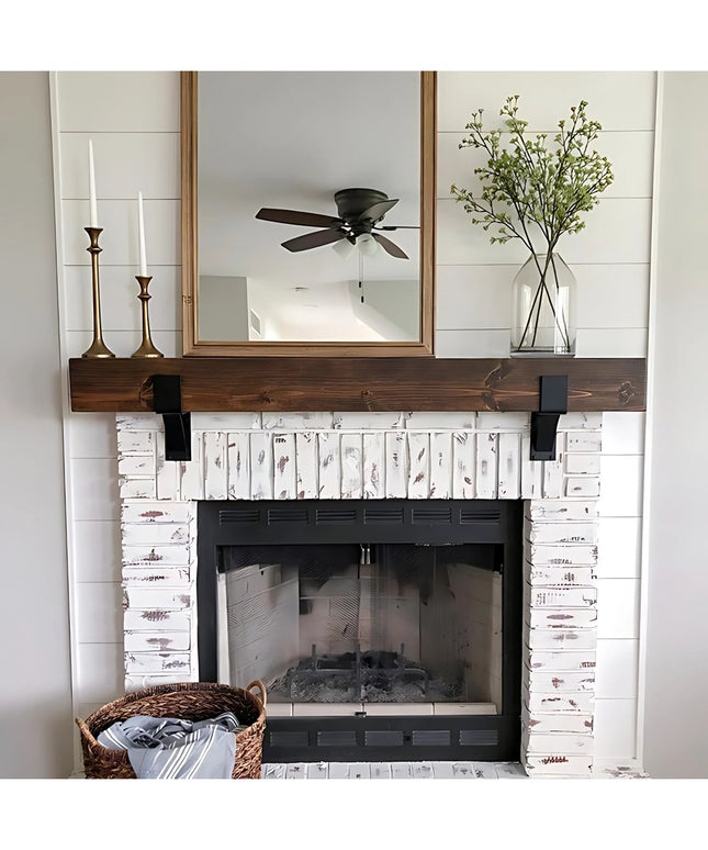 Black metal Seneca 3" Farmhouse Mantel Brackets supporting dark wood beam above white distressed brick fireplace by Indust...