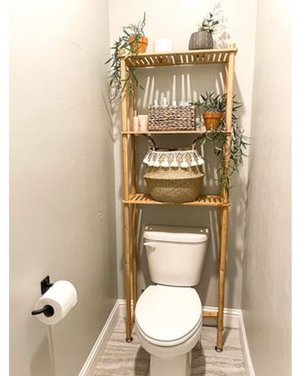 Bamboo over-the-toilet storage rack with three shelves holding wicker baskets and plants in modern bathroom, toilet paper ...