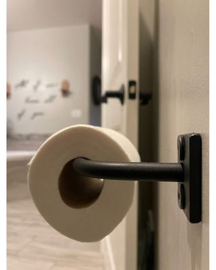 The Mitz black metal toilet paper holder by Industrial Farm Co mounted on white wall in modern bathroom setting