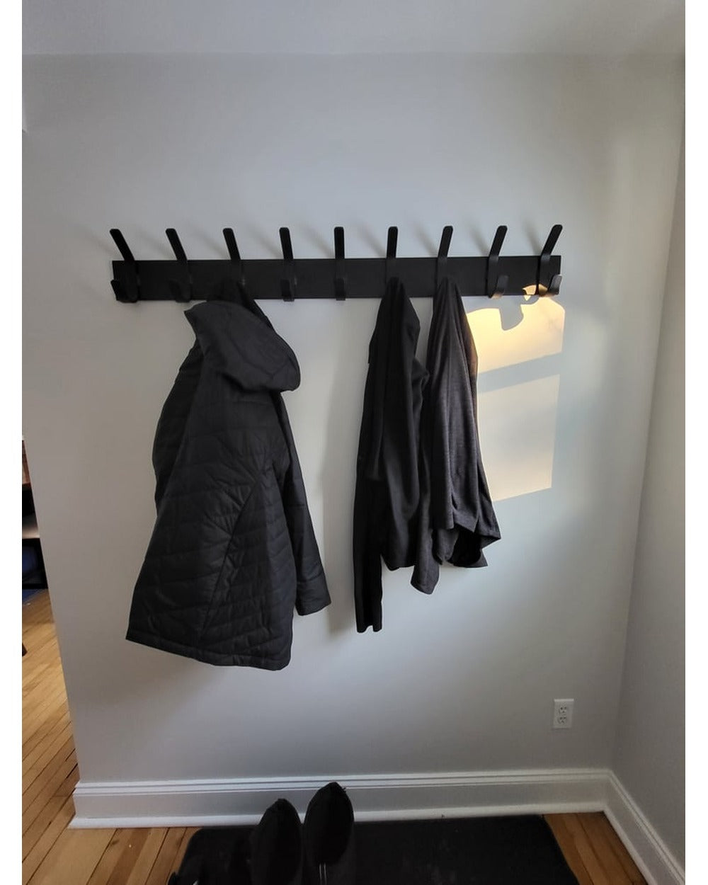 Metal Jacket Rack Black wall mounted metal coat rack with 9 hooks holding dark jackets ...