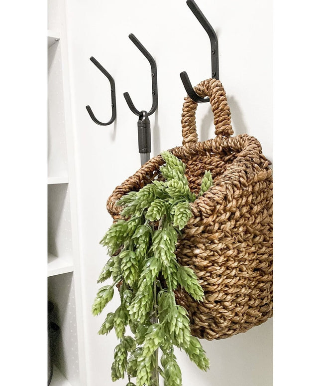 Black iron Stewart 1/2" Wide Double Hook mounted on white wall with woven basket and green fern, Industrial Farm Co wall hook