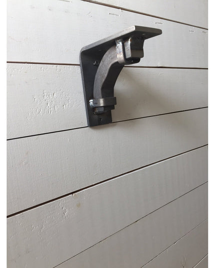 Black metal Butch Shelf Support bracket mounted on white shiplap wall showing curved design and mounting hardware from Ind...