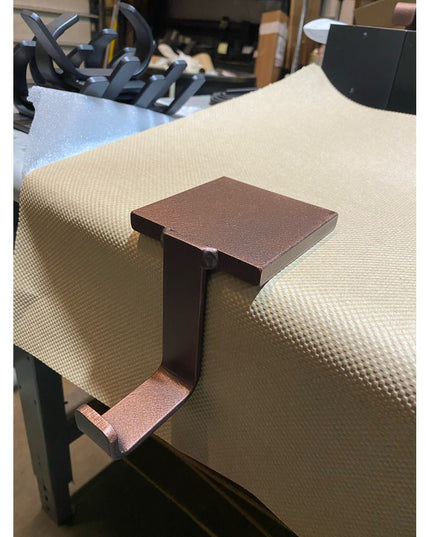 Industrial Farm Co Annie Stocking Holder in bronze finish, C-shaped metal clamp attached to cream upholstered chair arm in...