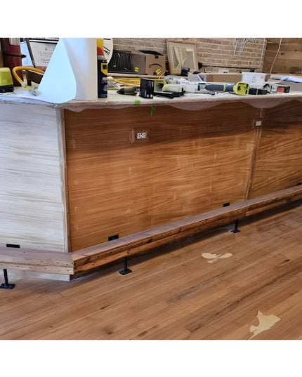 Black metal bar foot rail brackets installed under wooden kitchen island cabinetry with wood beam rail - Industrial Farm Co