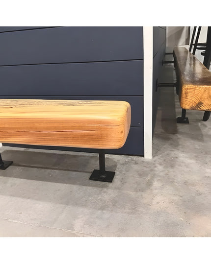 Black metal bar foot rail bracket supporting natural wood footrest rail against dark blue wall in modern industrial setting