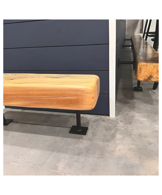 Black metal bar foot rail bracket supporting natural wood footrest rail against dark blue wall in modern industrial setting