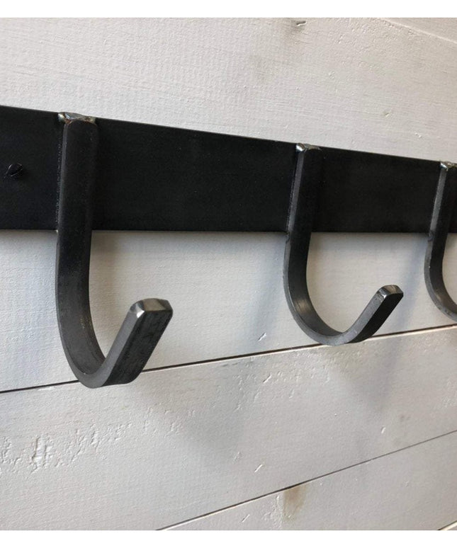 Black metal Camillus Style Coat Rack by Industrial Farm Co with four curved hooks mounted on white shiplap wall