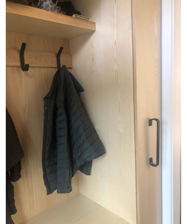 Black Long Beach Handle door pull by Industrial Farm Co mounted on light wood closet door with hanging jacket and storage ...