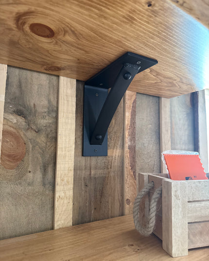 Wooden shelf with black metal bracket against a wooden wall.