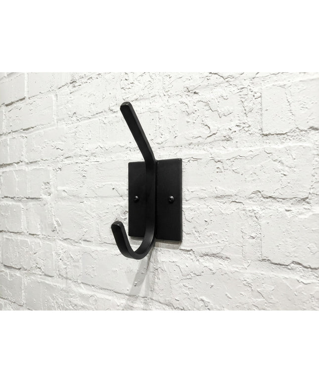 Black metal Felix Wall Hook by Industrial Farm Co mounted on white painted brick wall, featuring minimalist design with si...