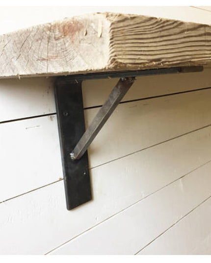 Black metal Oneida Shelf Bracket from Industrial Farm Co supporting reclaimed wood beam on white shiplap wall with diagona...
