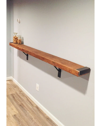 Oneida black metal shelf bracket supporting rustic wood floating shelf on white wall with glass jars - Industrial Farm Co