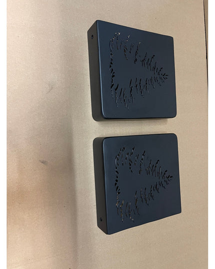 Two dark blue square wooden mantel end caps with raised evergreen tree designs mounted on beige wall by Industrial Farm Co