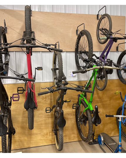 Black metal Logan Wall Mounted Bike Rack by Industrial Farm Co holding multiple mountain bikes on wooden garage wall stora...