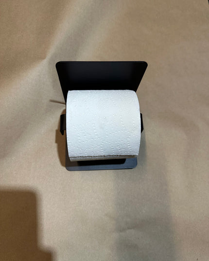 Roll of toilet paper on a black holder against a beige background