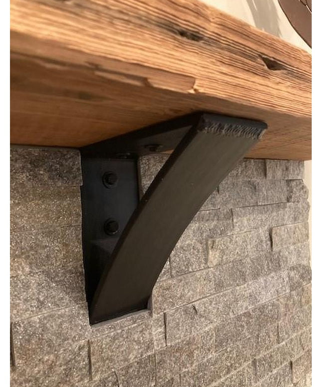 The Eleanor Minimal Steel Bracket by Industrial Farm Co in matte black finish supporting a wood shelf against textured sto...
