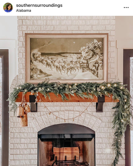 Decorative fireplace with mantel garland and framed artwork above.