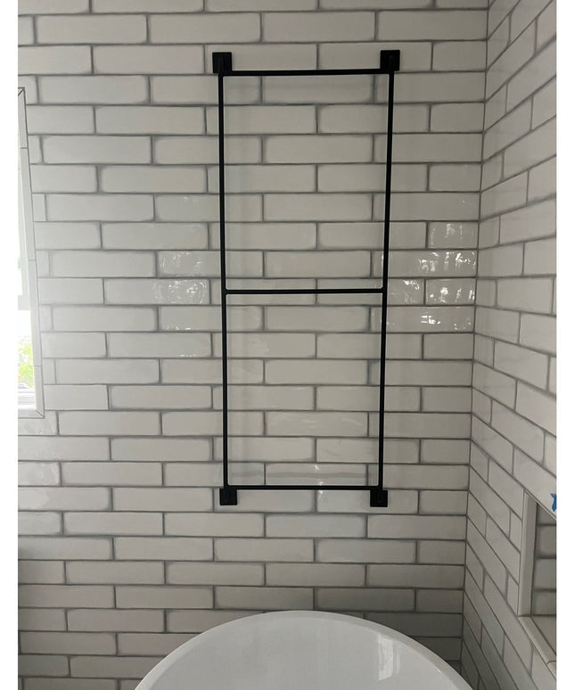 Black metal Arianna Wall Mounted Ladder by Industrial Farm Co displayed against white subway tile bathroom wall above toilet