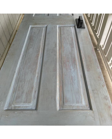 Black metal Lockport Pull door handle mounted on weathered gray wooden door with raised panel design from Industrial Farm Co