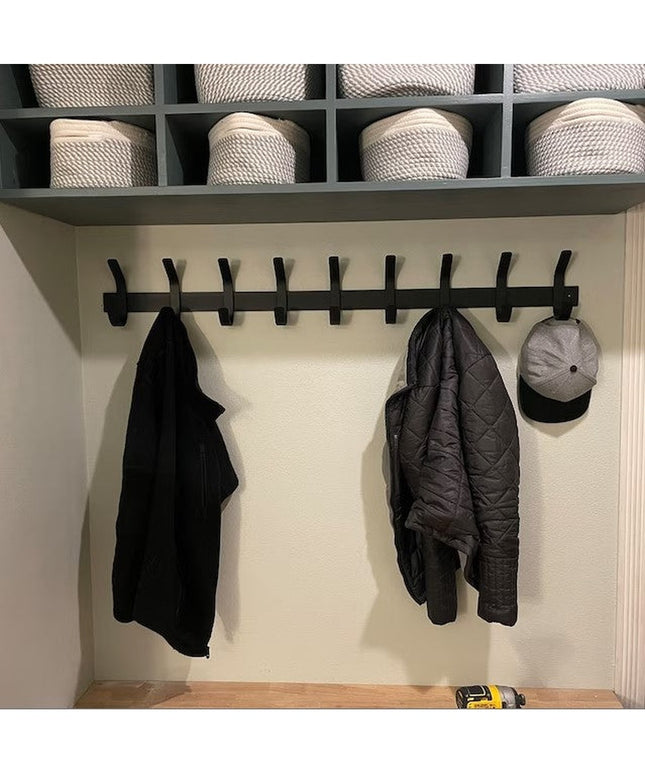 Black metal Christopher Double Hook Coat Rack by Industrial Farm Co mounted on white wall with baskets above, holding dark...
