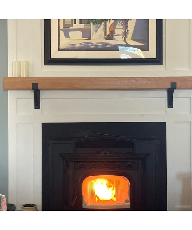 Black metal Saratoga Shelf Support Brackets by Industrial Farm Co supporting natural wood mantel above white fireplace