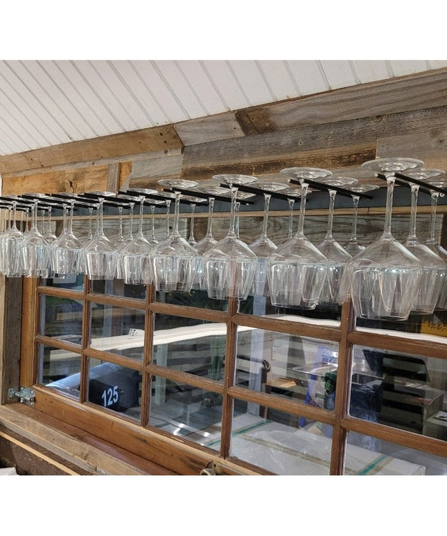 White Plains Wine Glass Rack by Industrial Farm Co mounted under rustic wooden beams holding multiple wine glasses in mode...