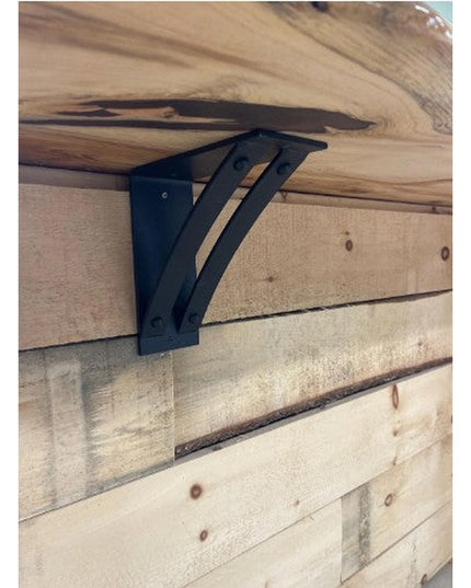 Black metal Jamestown 4" Wide Shelf Bracket by Industrial Farm Co mounted on rustic wood beam supporting live edge wooden ...