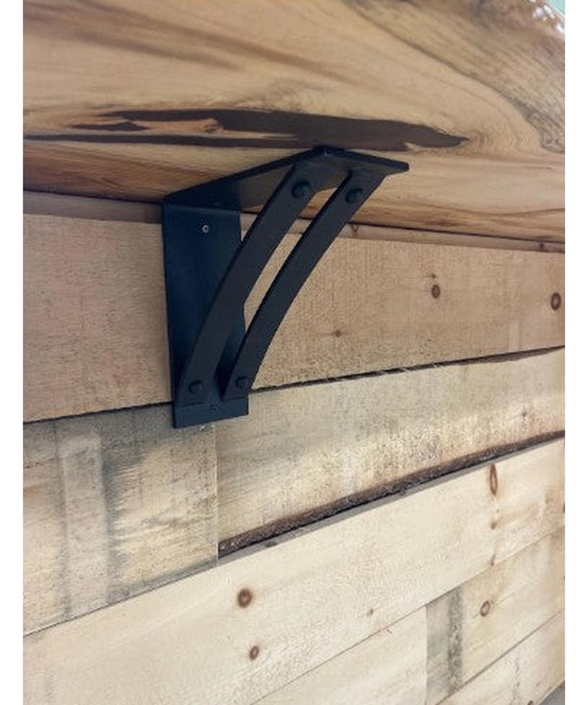 Black metal Jamestown 4" Wide Shelf Bracket by Industrial Farm Co mounted on rustic wood beam supporting live edge wooden ...