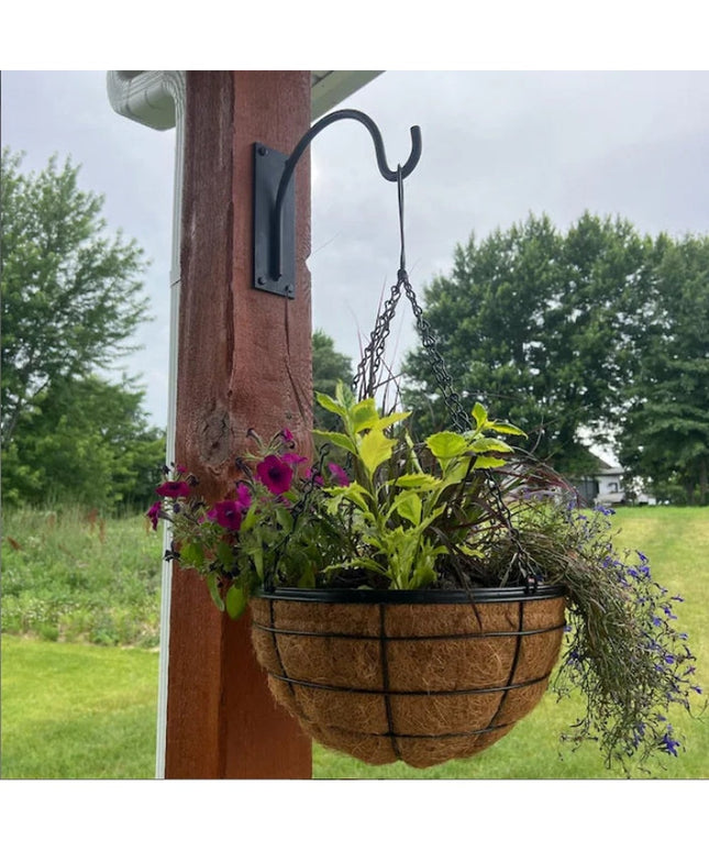 Black metal Gregory Shepherd Hook by Industrial Farm Co mounted on wooden post holding coconut fiber hanging basket with c...