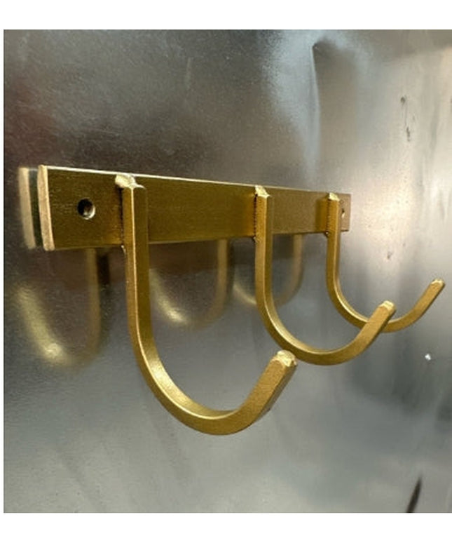 Gold metal wall-mounted key rack with 4 U-shaped hooks by Industrial Farm Co, showing modern rustic design on concrete wall
