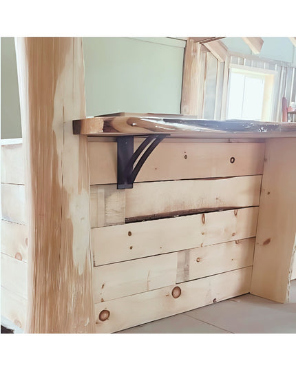 Black metal Jamestown 4" wide shelf bracket supporting wooden shelf on rustic pine wood construction, showing Industrial F...