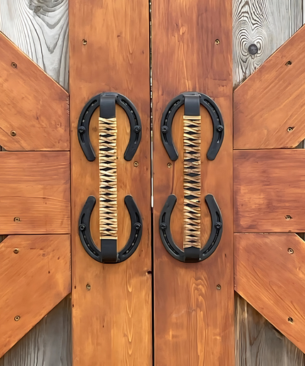 Horse shoe handles wrapped with leather braided handles mounted on barn doors outside.