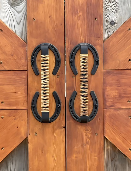 Horse shoe handles wrapped with leather braided handles mounted on barn doors outside.