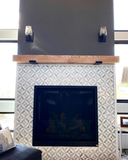 Modern fireplace with decorative tiles and wooden mantel in a living room setting.