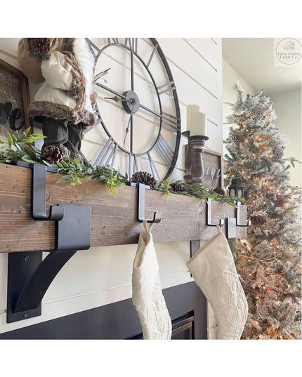 Rustic wooden Annie Stocking Holder shelf with black metal brackets displaying cream stockings, greenery garland, and larg...