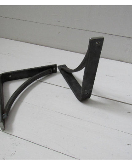 Black steel Oak Hill 1 inch industrial shelf brackets with curved support bars on white wooden surface by Industrial Farm Co