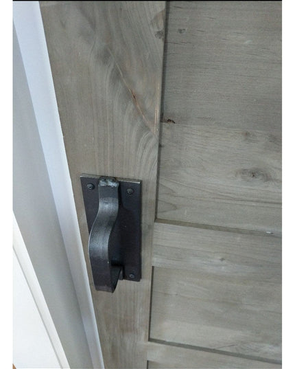 Black metal Lockport Pull door handle mounted on weathered gray wood barn door by Industrial Farm Co