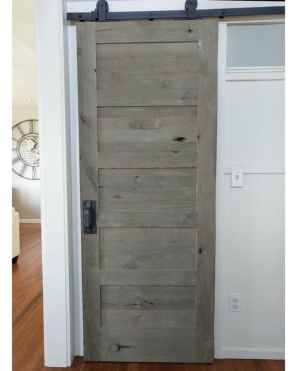 Rustic gray weathered wood barn door with black metal Lockport Pull handle by Industrial Farm Co on sliding track hardware