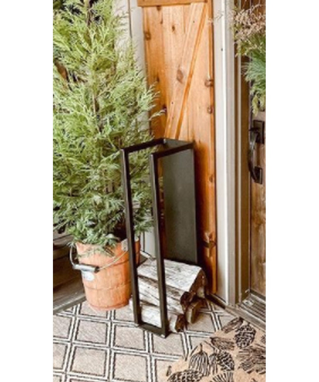 Black metal Toby Firewood Holder by Industrial Farm Co displayed on patterned tile patio with terracotta plant pot and wov...