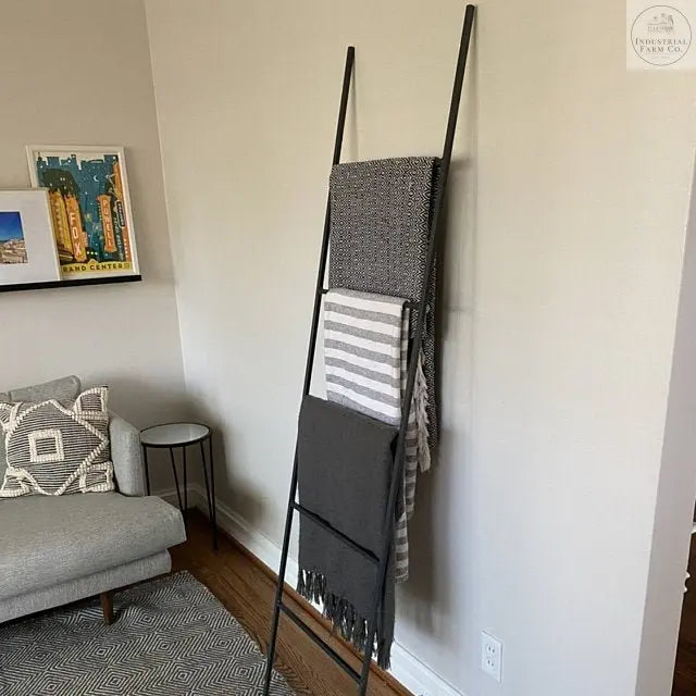 A metal blanket ladder with a sleek, minimalist design. The ladder stands upright with evenly spaced rungs, perfect for draping and displaying blankets or throws. It has a sturdy frame and a smooth finish, adding a modern and functional touch to any room.